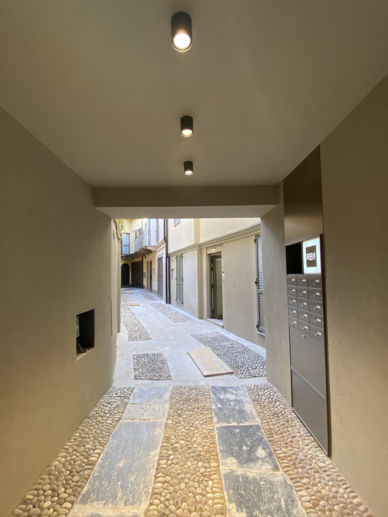 Centro Storico di Monza_03-PF-Archistudio Passaggio coperto con faretti a soffitto che dà su una stradina acciottolata del centro di Monza