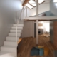 Render di un soppalco con scala bianca e parquet, con la cucina sullo sfondo