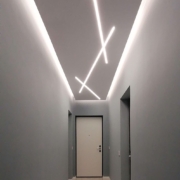 Corridoio d'ingresso con luci lineari a soffitto, porta bianca e pavimento di marmo