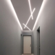 Corridoio d'ingresso con luci lineari a soffitto, porta bianca e pavimento di marmo